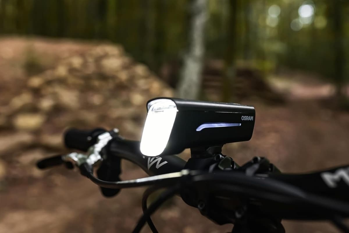 Phare avant OSRAM LEDsBIKE Race 50 éclairant un sentier, fixé sur le guidon
